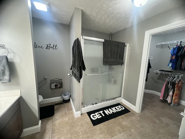 bathroom with vanity, a shower with shower door, and a textured ceiling