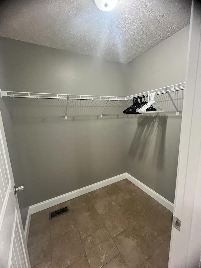 walk in closet featuring dark tile patterned floors