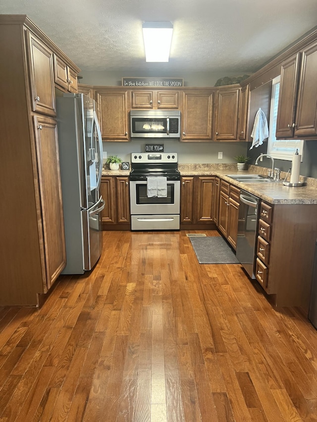 kitchen featuring dark wood-type flooring, appliances with stainless steel finishes, sink, and a textured ceiling