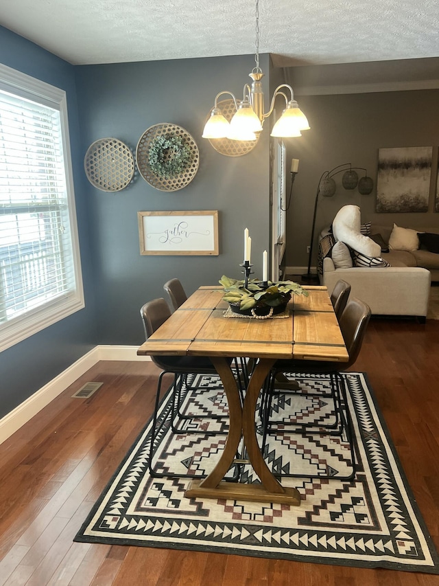 dining area with hardwood / wood-style floors, a notable chandelier, and a textured ceiling