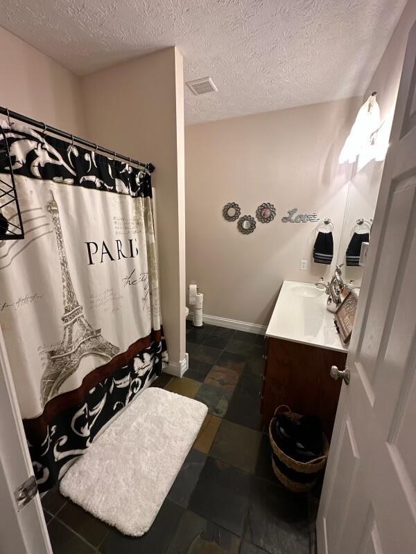 bathroom with a shower with curtain, vanity, and a textured ceiling