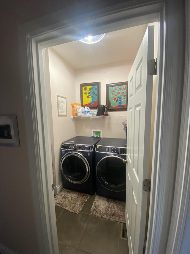 laundry area with dark tile patterned floors and washer and dryer