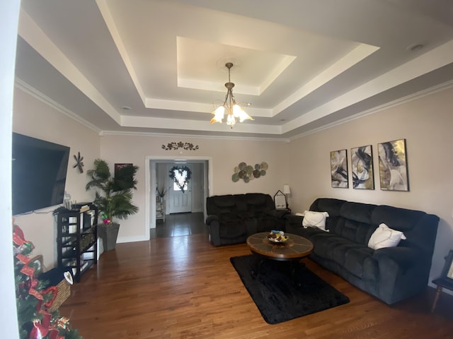 living room with crown molding, a tray ceiling, a chandelier, and hardwood / wood-style flooring