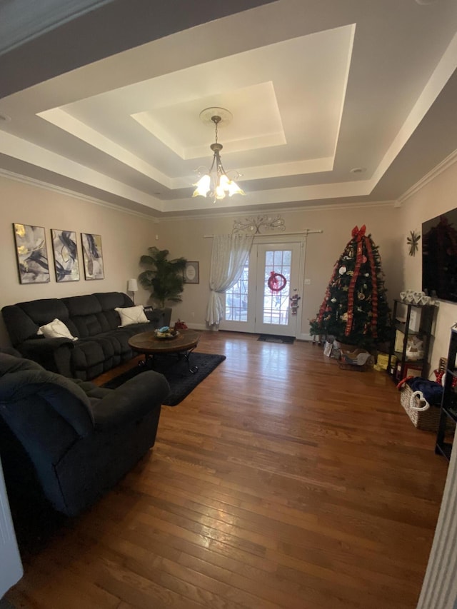 living room with an inviting chandelier, dark hardwood / wood-style floors, and a raised ceiling