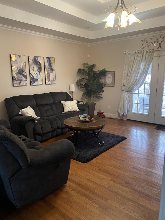 living room featuring a notable chandelier, crown molding, wood-type flooring, and a raised ceiling