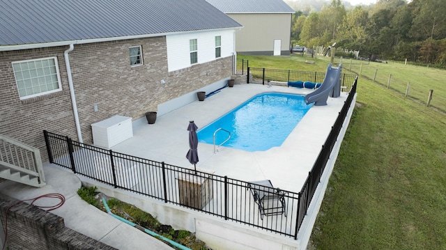 view of swimming pool featuring a lawn and a water slide