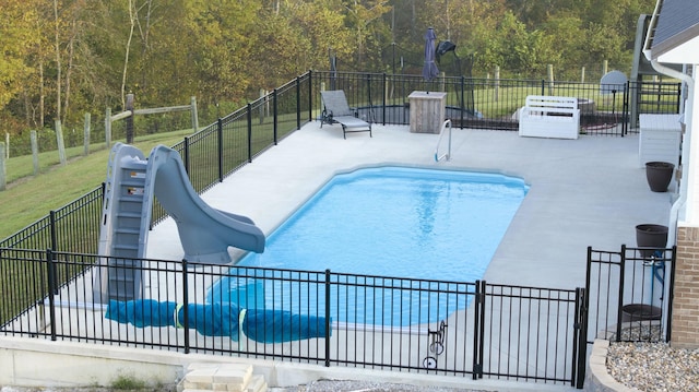 view of swimming pool featuring a patio area, a lawn, and a water slide