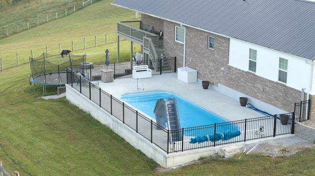 view of pool featuring a patio area, a rural view, a lawn, and a trampoline