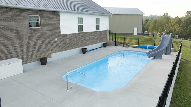 view of swimming pool featuring a patio area, a yard, and a water slide