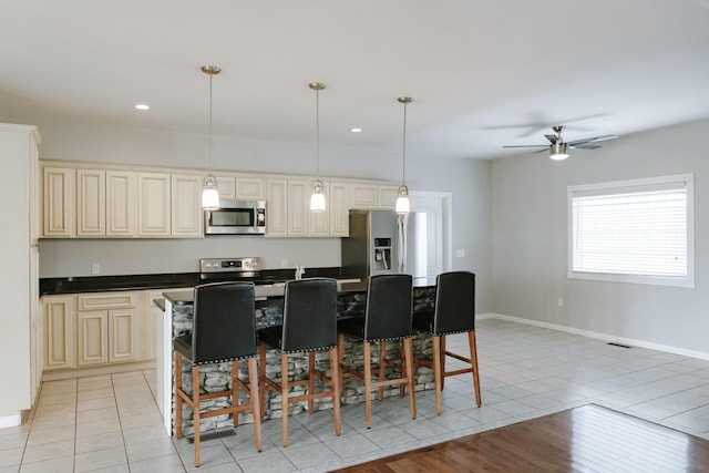 kitchen with decorative light fixtures, cream cabinetry, and stainless steel appliances