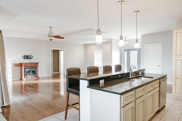 kitchen featuring sink, cream cabinetry, an island with sink, a kitchen bar, and dark stone countertops