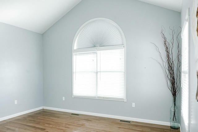 empty room with vaulted ceiling and light hardwood / wood-style flooring