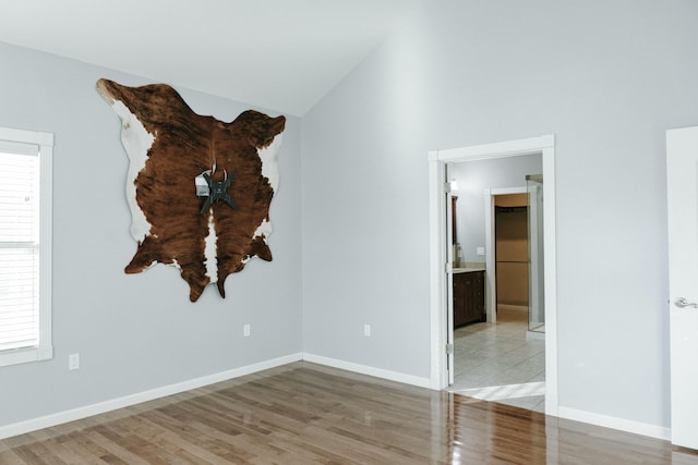 empty room with a wealth of natural light, light hardwood / wood-style flooring, and vaulted ceiling