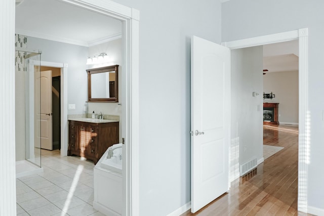 corridor featuring sink, light tile patterned floors, and ornamental molding