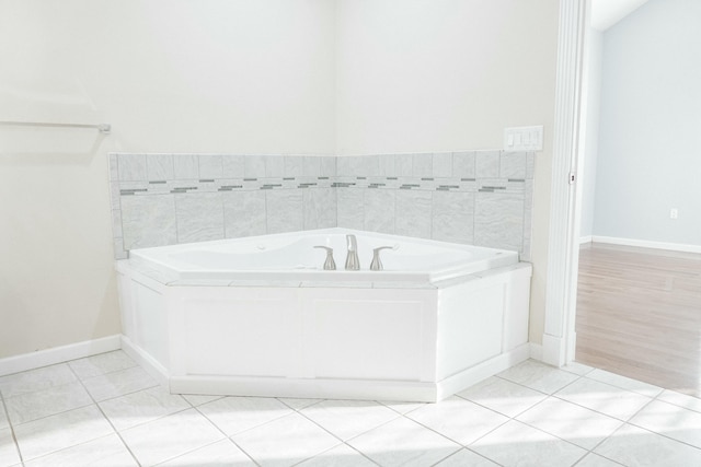 bathroom with a relaxing tiled tub and tile patterned floors