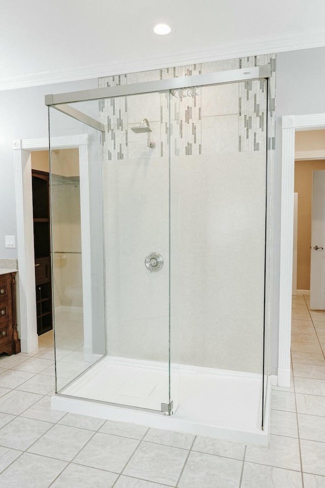 bathroom with tile patterned floors, ornamental molding, an enclosed shower, and vanity