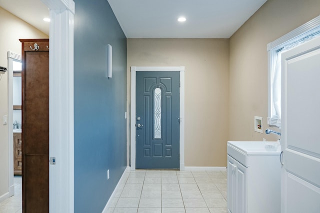 interior space with cabinets, sink, hookup for a washing machine, and light tile patterned flooring