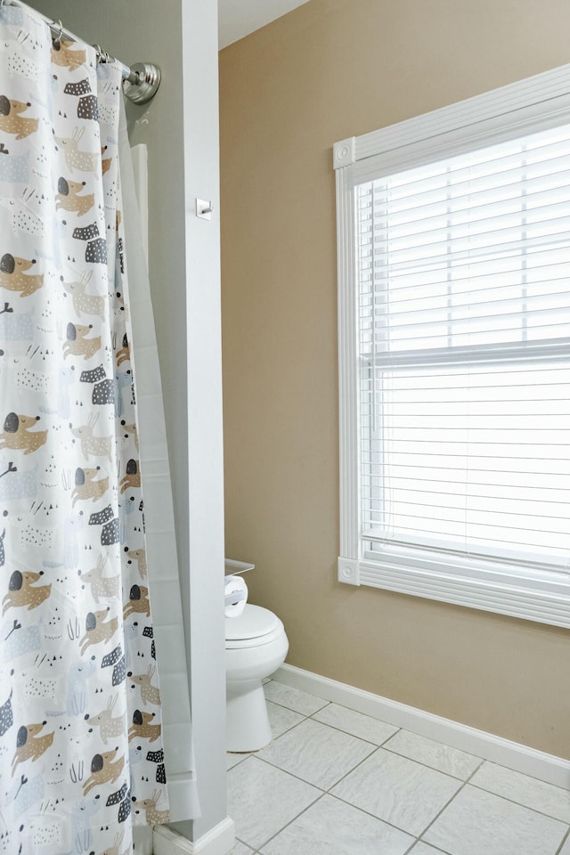 bathroom featuring toilet, a shower with shower curtain, and tile patterned flooring