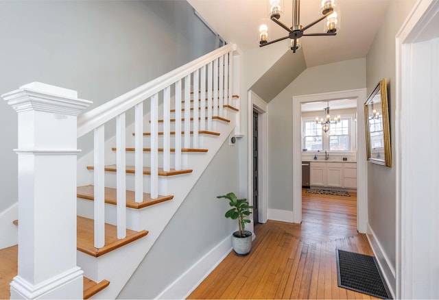 stairs featuring sink, hardwood / wood-style floors, and a notable chandelier