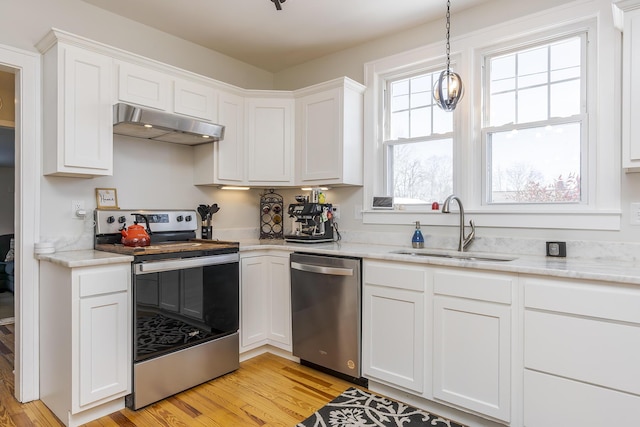 kitchen with appliances with stainless steel finishes, sink, white cabinets, and light wood-type flooring