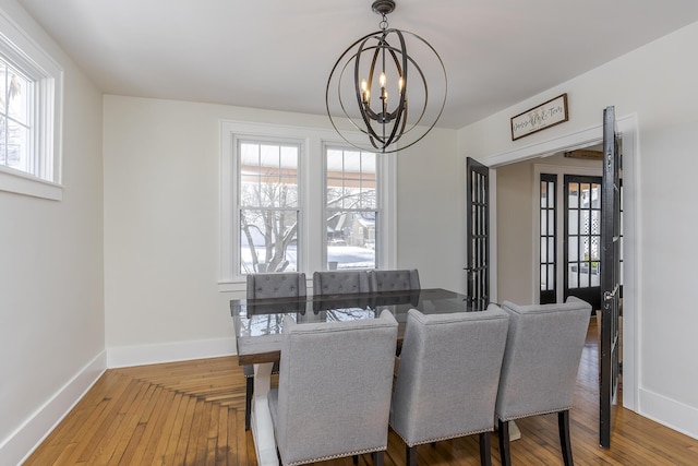 dining room with an inviting chandelier, plenty of natural light, and wood-type flooring