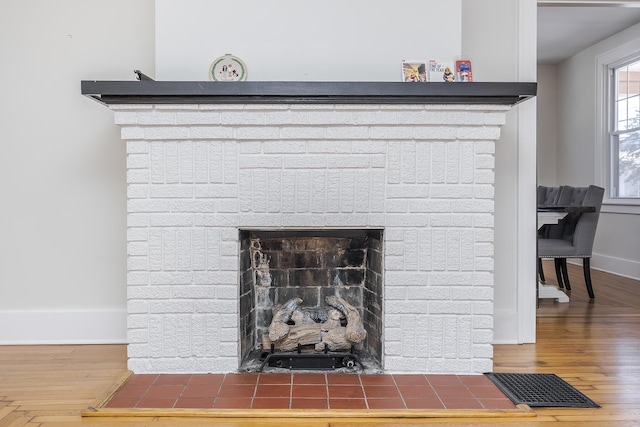 interior details featuring a brick fireplace and hardwood / wood-style flooring