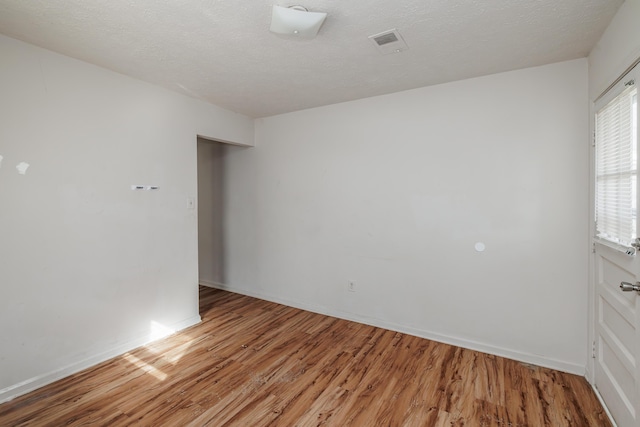 spare room with a textured ceiling and light hardwood / wood-style flooring