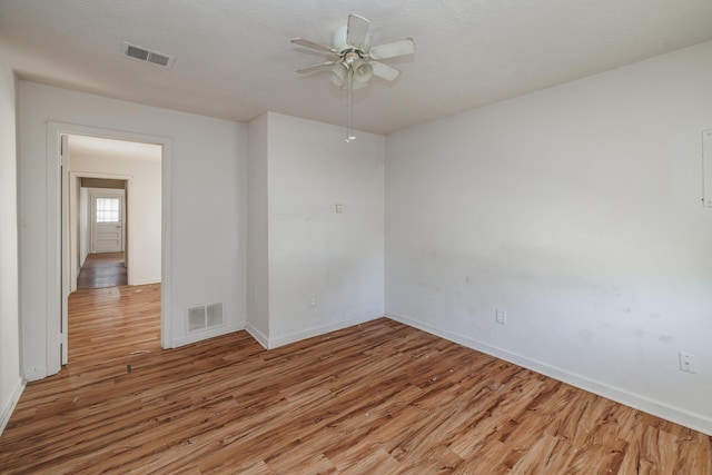 empty room with ceiling fan and light hardwood / wood-style flooring