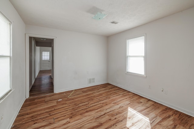 spare room featuring a textured ceiling and light hardwood / wood-style flooring