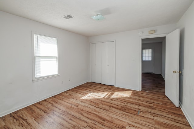 unfurnished bedroom with light hardwood / wood-style floors, a closet, and a textured ceiling