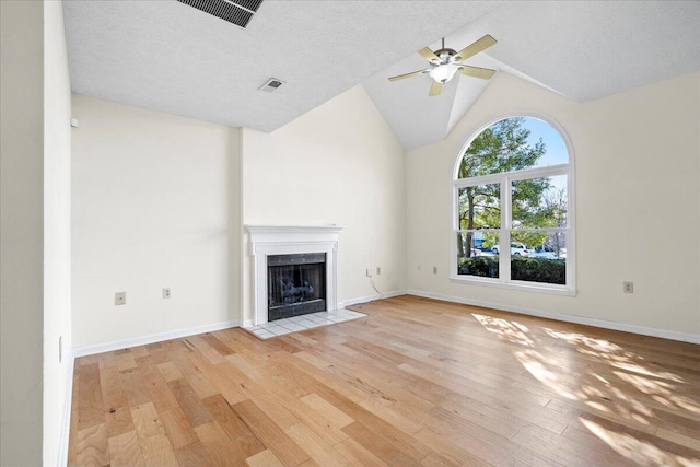 unfurnished living room with vaulted ceiling, a textured ceiling, ceiling fan, and light wood-type flooring