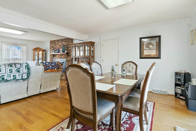 dining space featuring light hardwood / wood-style flooring, crown molding, and a fireplace