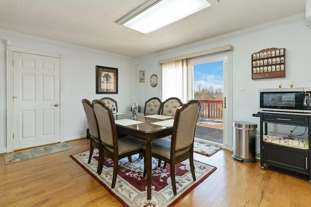 dining room with light wood-type flooring, a textured ceiling, and crown molding