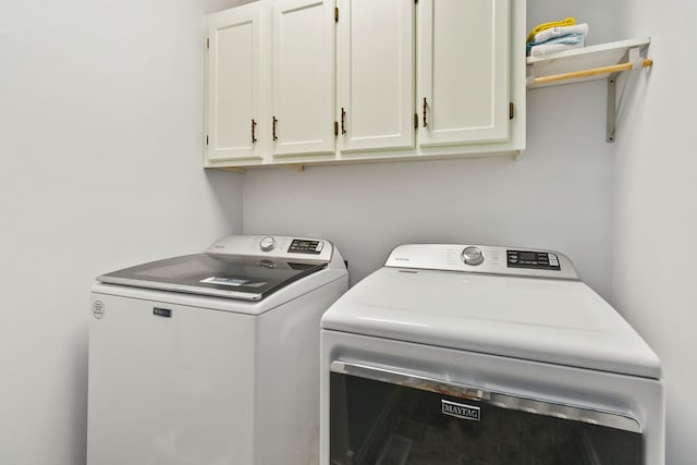 clothes washing area featuring washing machine and dryer and cabinets