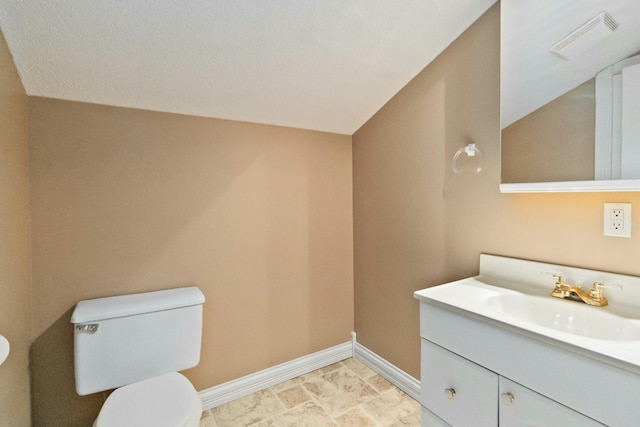 bathroom with toilet, vanity, and lofted ceiling