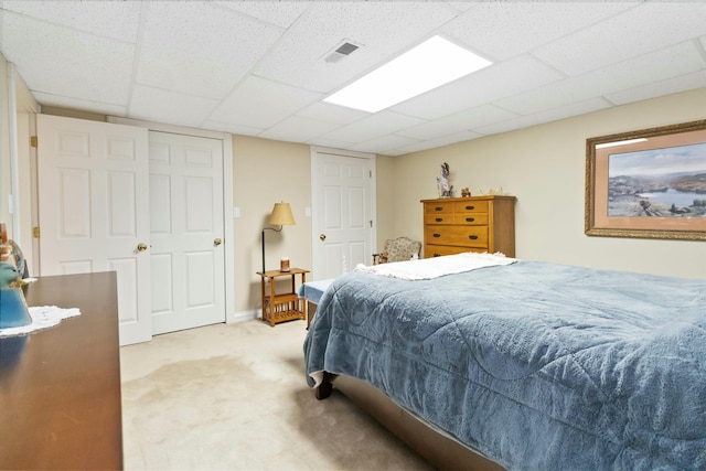 carpeted bedroom featuring a drop ceiling and a closet