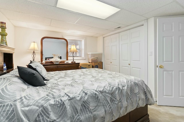 bedroom featuring a drop ceiling, a closet, and carpet flooring