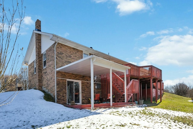 snow covered back of property featuring a wooden deck