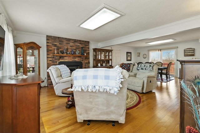 living room with light hardwood / wood-style floors, a textured ceiling, ornamental molding, and a fireplace