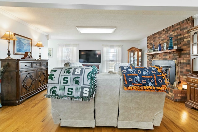 living room featuring a brick fireplace, light hardwood / wood-style floors, a textured ceiling, and crown molding