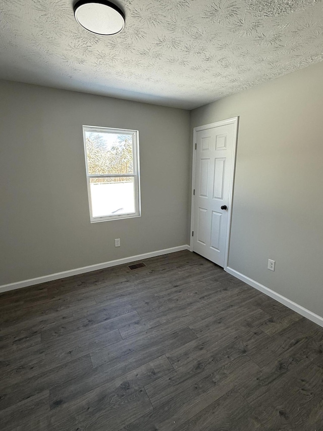 spare room with dark hardwood / wood-style floors and a textured ceiling