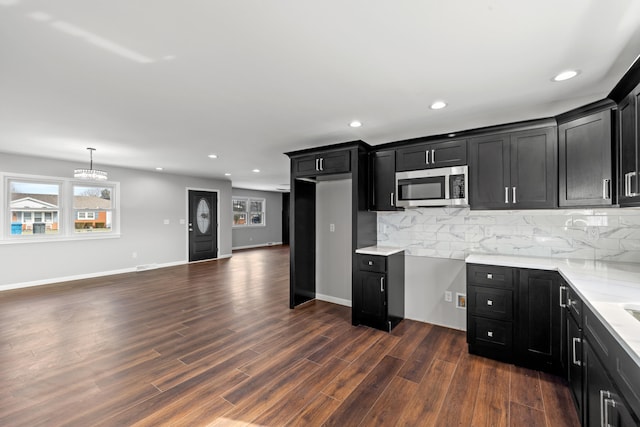 kitchen featuring pendant lighting, backsplash, light stone countertops, and dark hardwood / wood-style floors