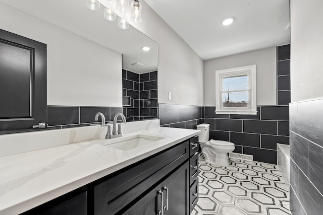 bathroom with tile walls, vanity, tile patterned flooring, and toilet