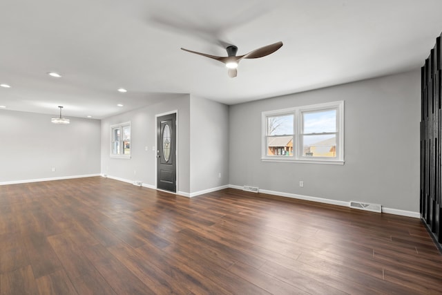 unfurnished room with dark wood-type flooring and ceiling fan with notable chandelier