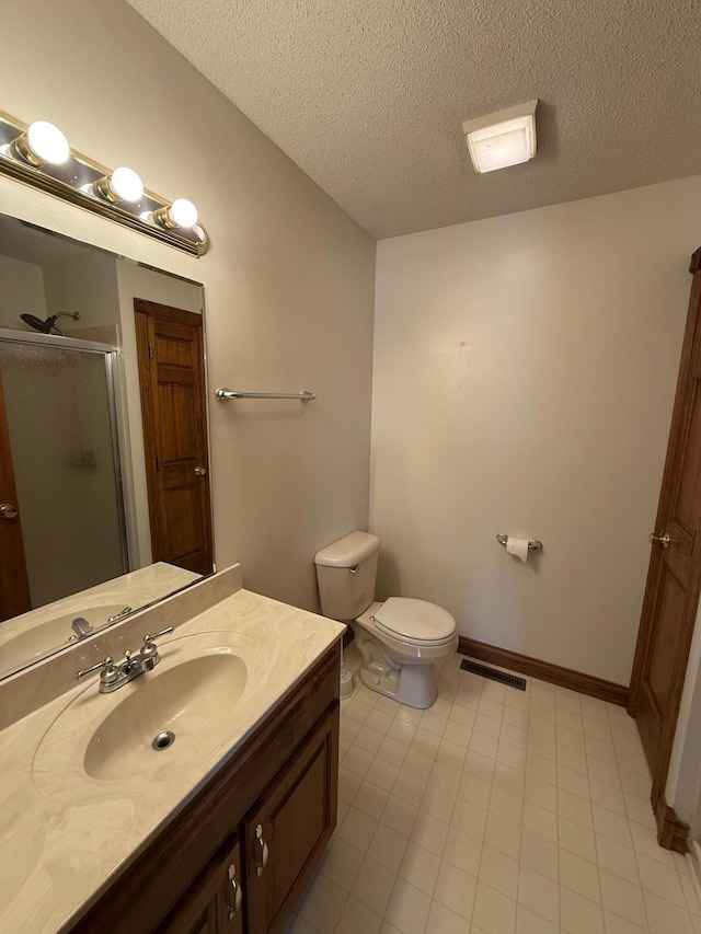 bathroom featuring a textured ceiling, an enclosed shower, vanity, and toilet