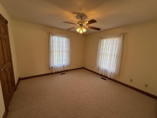 carpeted spare room featuring plenty of natural light, a textured ceiling, and ceiling fan