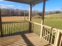 wooden deck with a rural view and a lawn