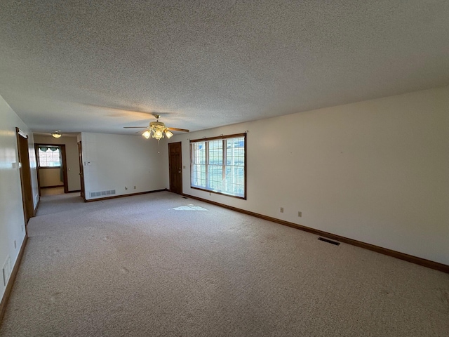 unfurnished room with ceiling fan, a textured ceiling, and light carpet