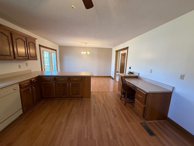 kitchen featuring a textured ceiling, white dishwasher, kitchen peninsula, pendant lighting, and hardwood / wood-style floors