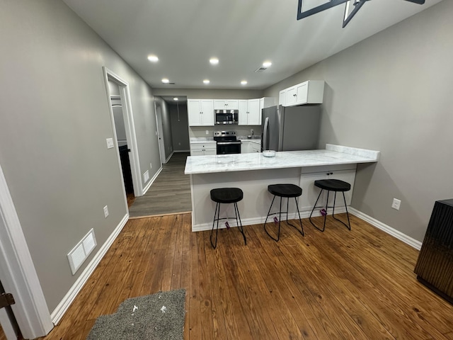 kitchen with stainless steel appliances, white cabinetry, dark wood-type flooring, and kitchen peninsula